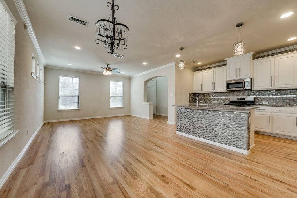 636 S Greenville Avenue, Richardson, TX 75081 Kitchen with light hardwood / wood-style flooring, decorative light fixtures, ceiling fan with notable chandelier, stainless steel appliances, and white cabinetry