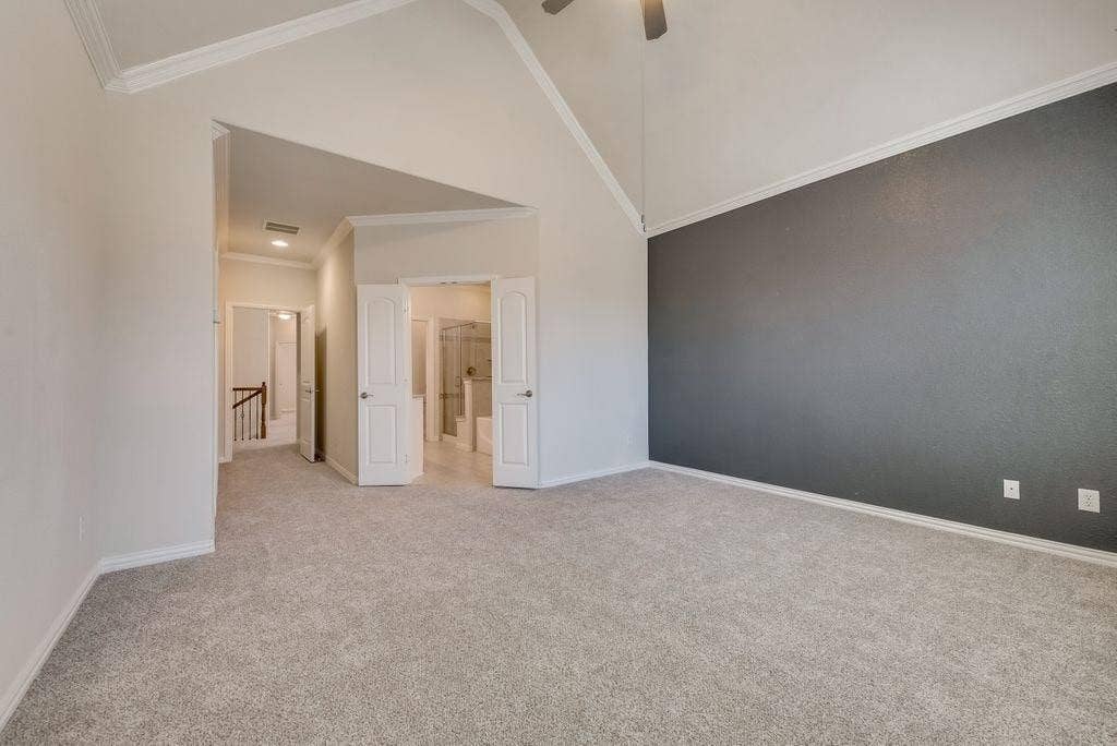 636 S Greenville Avenue, Richardson, TX 75081 Carpeted empty room featuring crown molding, high vaulted ceiling, and ceiling fan