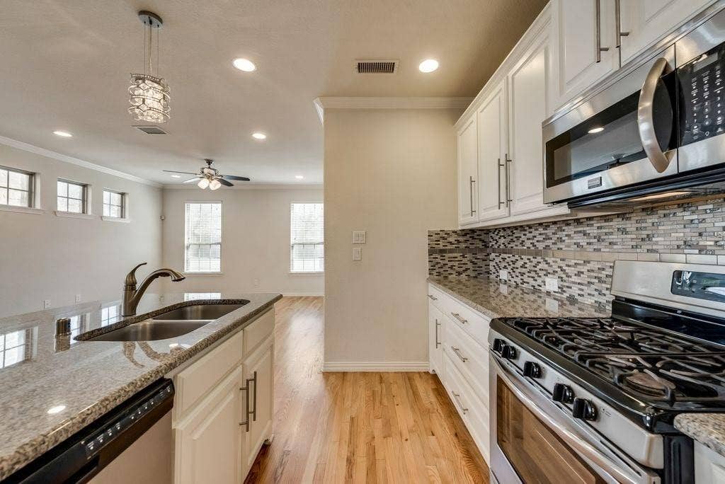 636 S Greenville Avenue, Richardson, TX 75081 Kitchen with pendant lighting, sink, light stone countertops, appliances with stainless steel finishes, and white cabinets