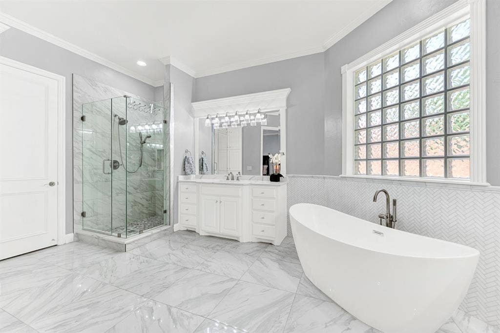 2608 LAWTON Lane, Plano, TX 75093 A seamless frameless glass shower features refined stone tile surrounds that complement the herringbone-patterned wall accents. Picture starting your mornings with a warm, refreshing shower before stepping out onto cool marble-look floors.
