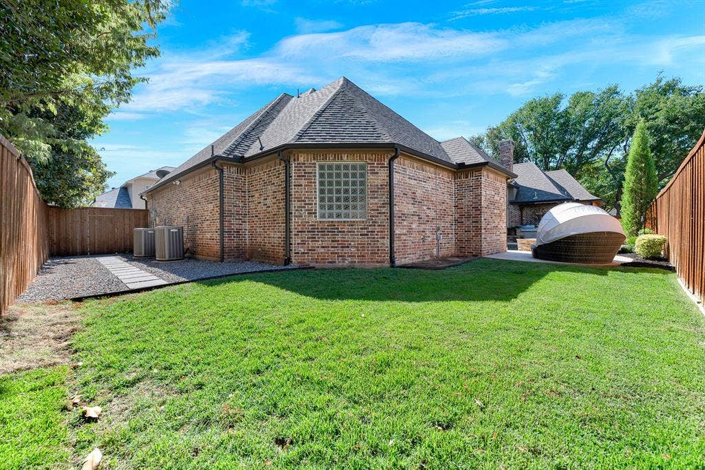 2608 LAWTON Lane, Plano, TX 75093 A neatly manicured lawn extends along the privacy-fenced border, highlighting the home's intricate rooflines and glass-block accent window. It is a wonderful space for pets to play freely or for enjoying quiet morning stretches outdoors.