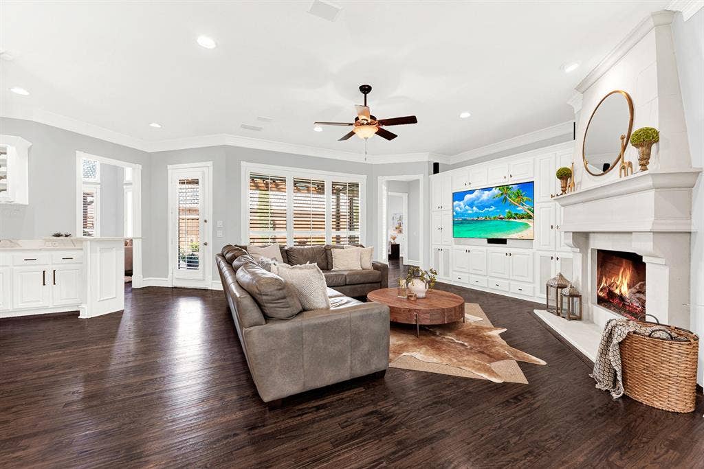 2608 LAWTON Lane, Plano, TX 75093 A stately stone-look fireplace hearth anchors the far wall, framed by full-height custom entertainment cabinetry and expansive pool-facing windows. Imagine hosting weekend game days with family gathered together in the warm glow of the fire.
