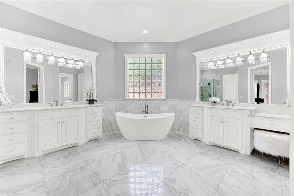2608 LAWTON Lane, Plano, TX 75093 A sleek freestanding soaking tub serves as a sculpted centerpiece beneath a privacy-glass window, flanked by dual vanities. You will love treating yourself to a spa-like bath soak at night with gentle overhead vanity light gleaming across the polished tile.