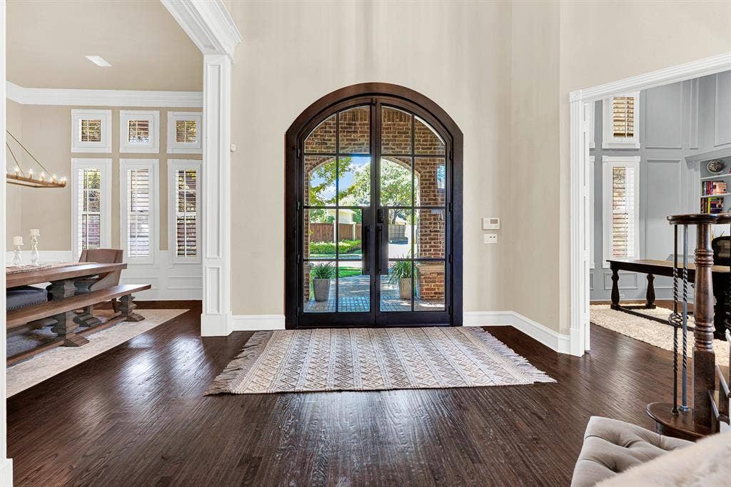 2608 LAWTON Lane, Plano, TX 75093 The grand iron-and-glass arched doorway frame fills the hall with soft natural light while offering clear views of the brick entryway. You will love welcoming friends through these glass doors as evening sets in and warm indoor light spill out onto the porch.