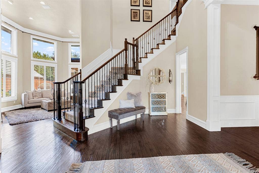 2608 LAWTON Lane, Plano, TX 75093 Rich hardwood floors anchor a dramatic open staircase that gracefully winds upward alongside towering high ceilings. Imagine returning home after a long day, kicking off your shoes, and relaxing as afternoon sunbeams stream through the grand windows