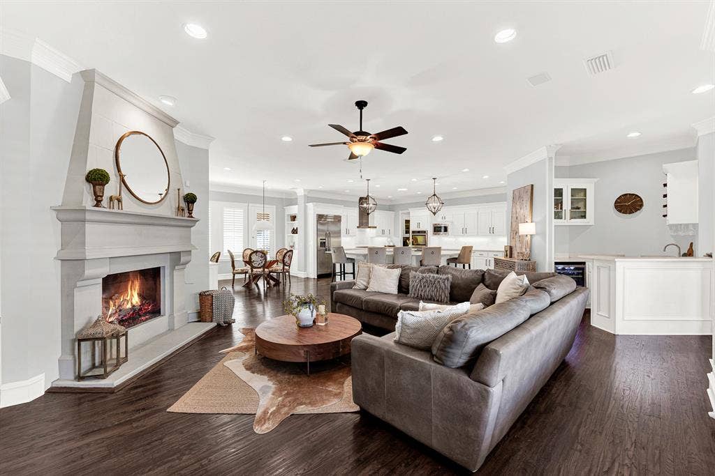 2608 LAWTON Lane, Plano, TX 75093 Recessed ceiling lighting and continuous dark hardwood floors create a vast, seamless flow connecting the living space, kitchen, and bar area. Picture throwing open the patio doors for effortless indoor-outdoor entertaining on warm summer evenings.