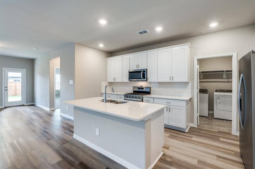 Kitchen featuring a central island with a solid surface countertop, white shaker-style cabinetry, subway tile backsplash, and wood-finish flooring