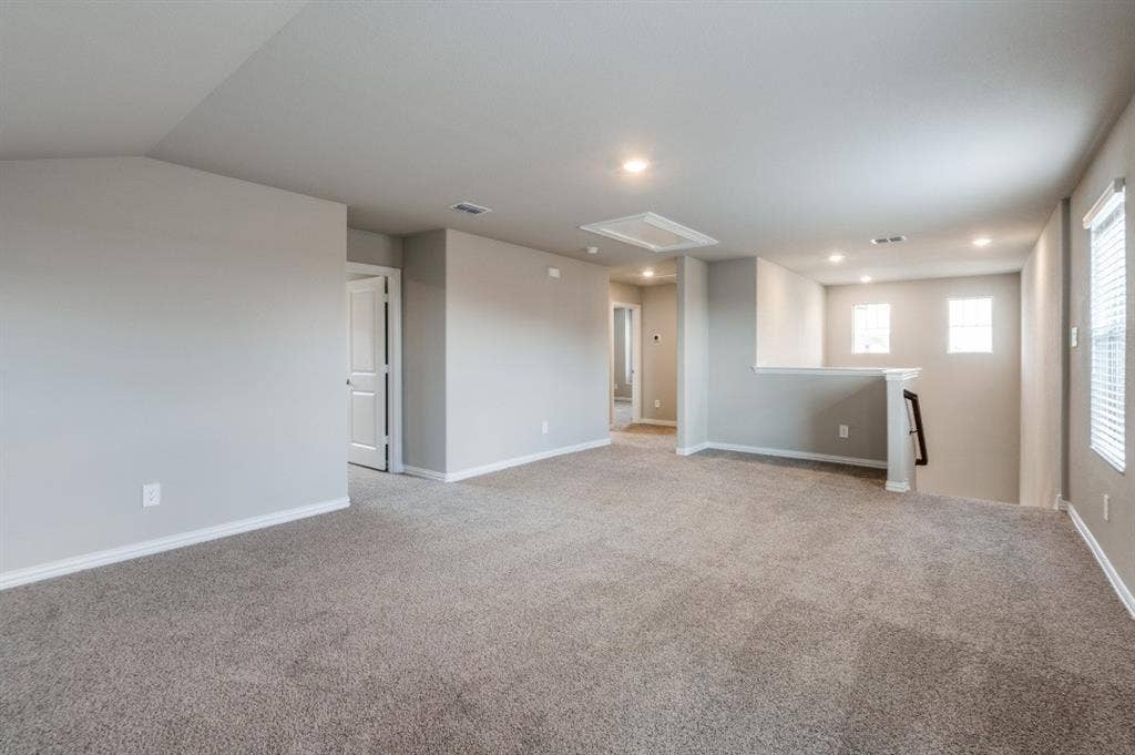 Neutral-toned interior space featuring wall-to-wall carpeting, recessed ceiling lighting, and multiple windows