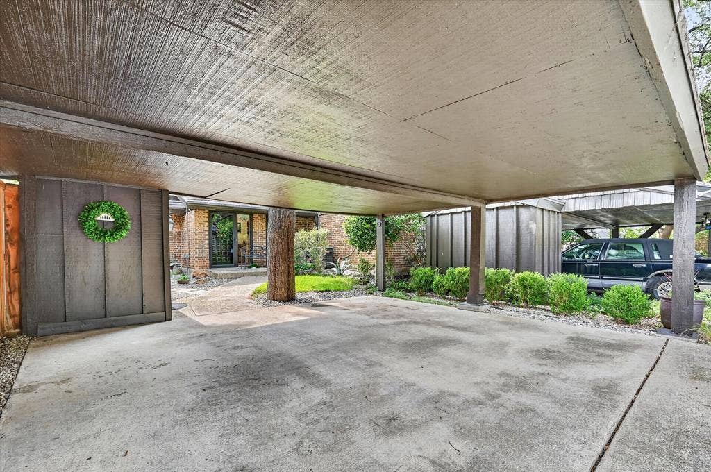 12627 Breckenridge Drive, #200, Dallas, TX 75230 Covered carport featuring a concrete parking surface, wood-paneled ceiling, and structural wood supports