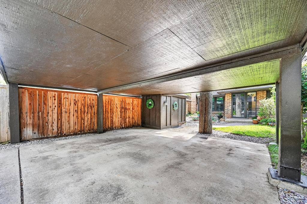 12627 Breckenridge Drive, #200, Dallas, TX 75230 Covered parking structure featuring a concrete pad, vertical wood siding, and integrated exterior storage unit