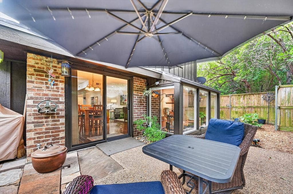 12627 Breckenridge Drive, #200, Dallas, TX 75230 Patio featuring exposed brick exterior, sliding glass door, stone-finish paving, and wooden perimeter fencing