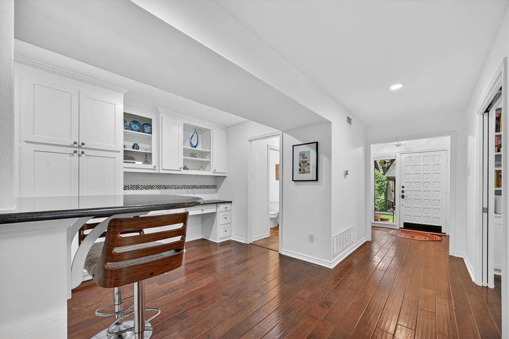 12627 Breckenridge Drive, #200, Dallas, TX 75230 Built-in white cabinetry, integrated desk workspace, dark solid-surface countertop, and wood-finish flooring