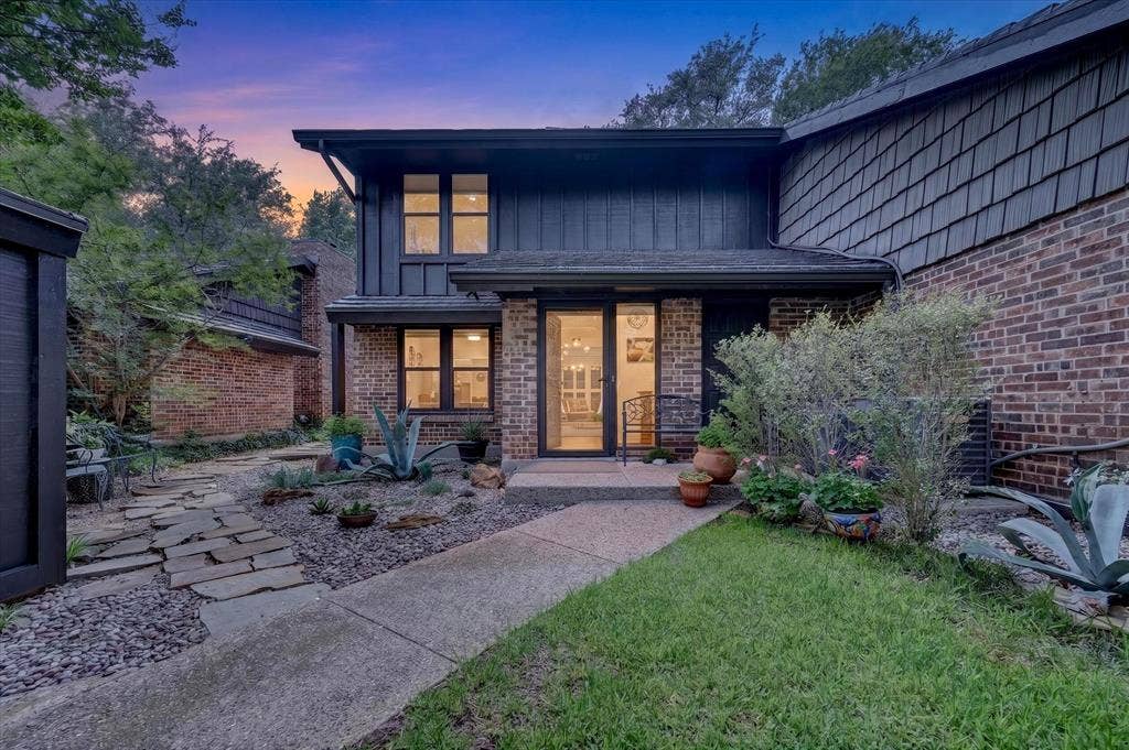 12627 Breckenridge Drive, #200, Dallas, TX 75230 Multi-level exterior featuring a combination of brick and vertical siding, stone-paved walkway, xeriscaped garden beds, and expansive multi-pane windows
