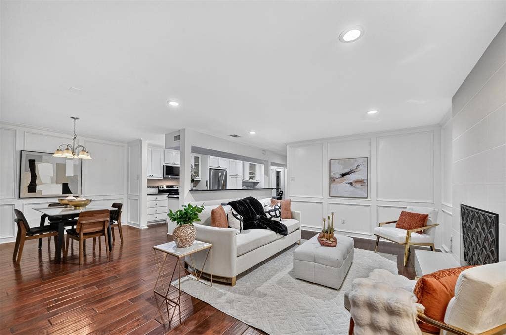 12627 Breckenridge Drive, #200, Dallas, TX 75230 Open-concept living space featuring wood-finish flooring, recessed lighting, white wainscoting, and a fireplace with a geometric-patterned metal screen
