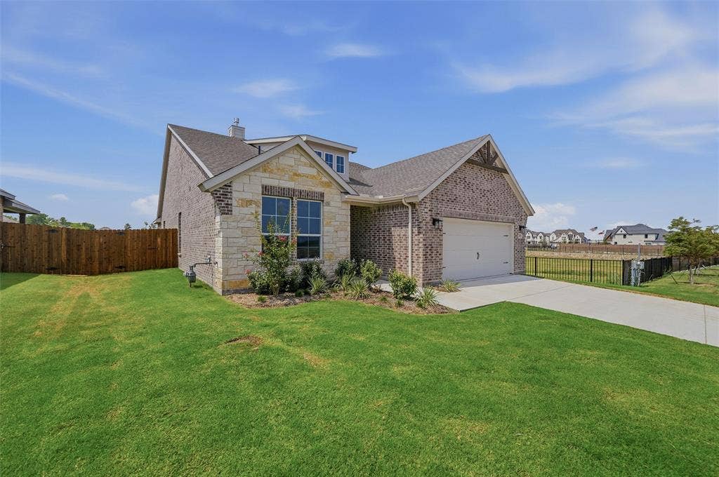 2109 Bluebird Lane, Anna, TX 75409 Brick exterior with stone accents, attached garage, concrete driveway, and a wood privacy fence