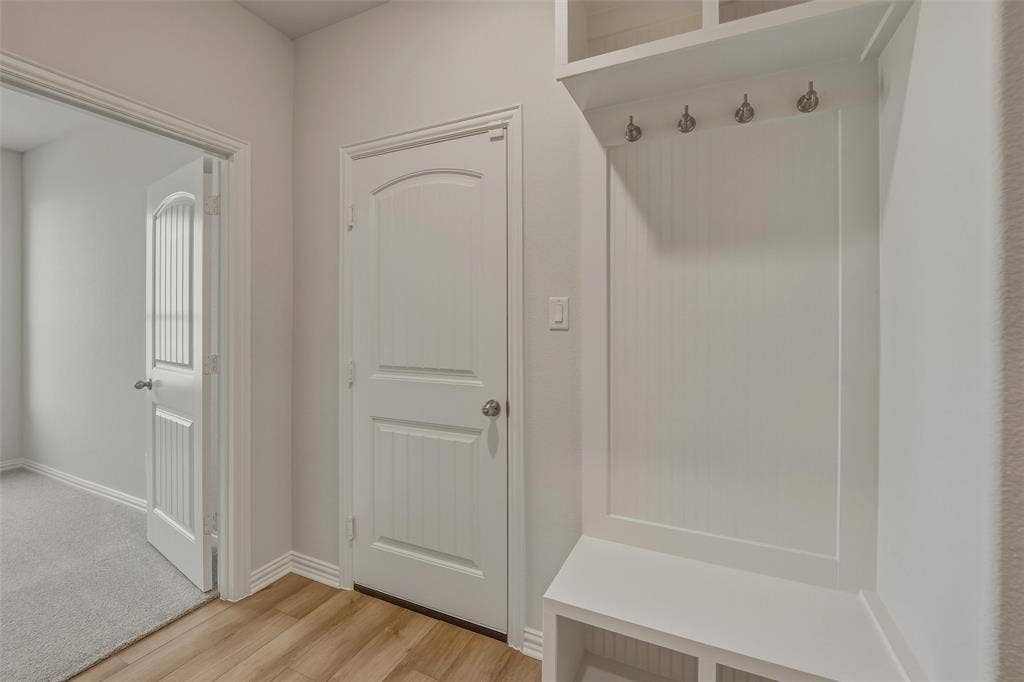 2109 Bluebird Lane, Anna, TX 75409 Built-in coat rack with storage cubbies, wood-finish flooring, and white paneled doors
