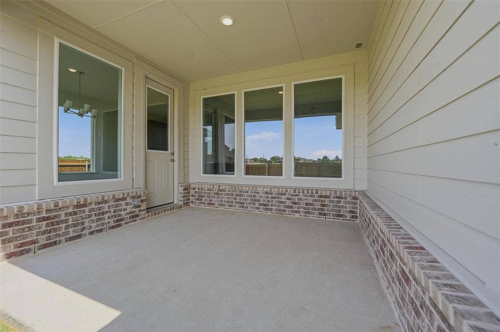 2109 Bluebird Lane, Anna, TX 75409 Covered patio featuring a concrete surface, brick wainscoting, a single entry door, and multiple windows