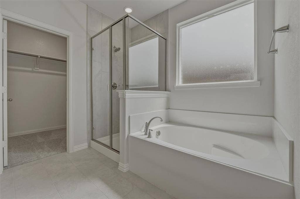 2109 Bluebird Lane, Anna, TX 75409 Built-in soaking tub, glass-enclosed shower, tiled shower surround, recessed lighting, and frosted window