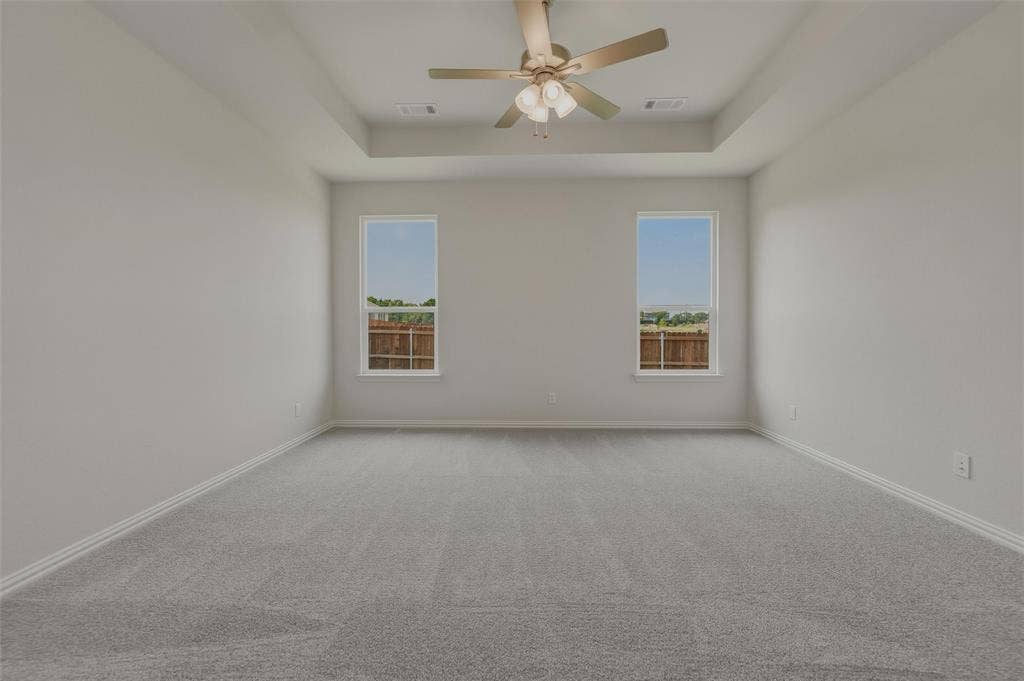 2109 Bluebird Lane, Anna, TX 75409 Tray ceiling with a ceiling fan, two windows, and gray carpeting