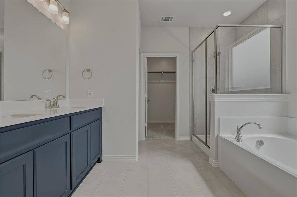 2109 Bluebird Lane, Anna, TX 75409 Dual vanity with a stone countertop and undermount sinks, glass-enclosed shower, built-in bathtub, and tile flooring