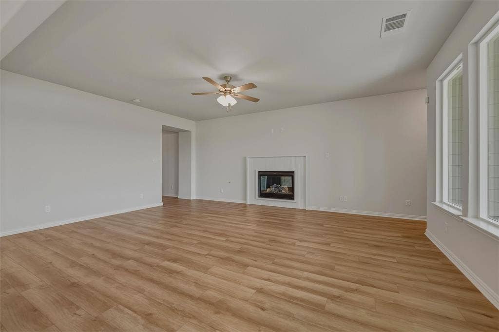 2109 Bluebird Lane, Anna, TX 75409 Wood-finish flooring throughout, multiple windows, and a built-in fireplace with a mantel