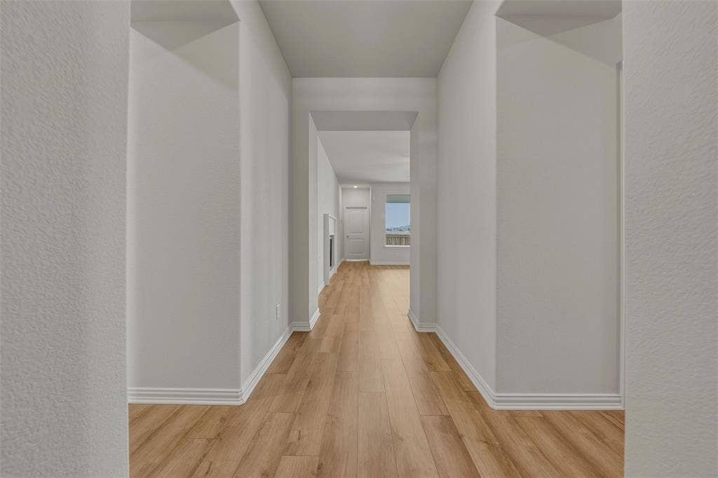 2109 Bluebird Lane, Anna, TX 75409 Hallway featuring wood-finish flooring, light-toned walls, and white trim