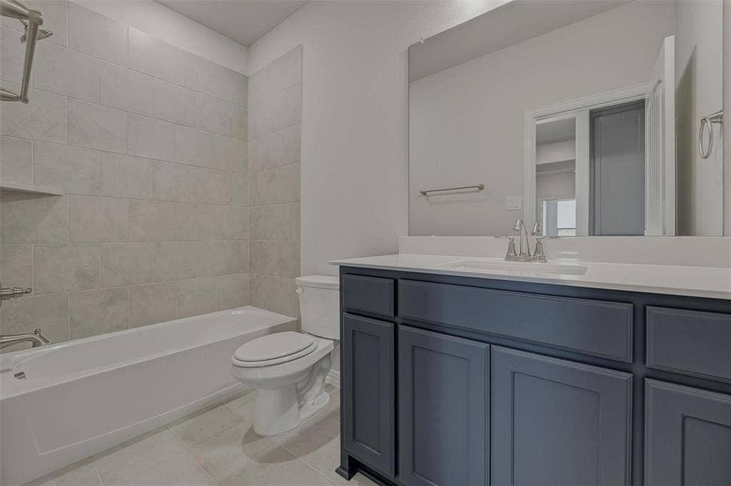 2109 Bluebird Lane, Anna, TX 75409 Tub-shower combination with tiled surround, built-in shelving, and a vanity featuring a single sink and cabinet storage
