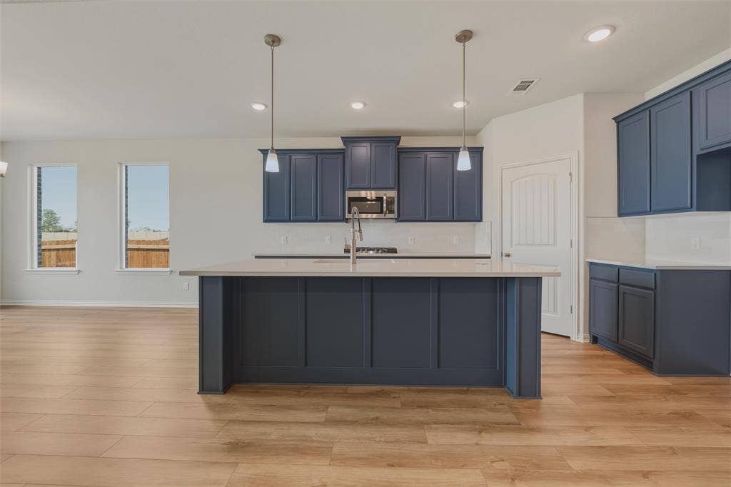 2109 Bluebird Lane, Anna, TX 75409 Kitchen featuring wood-finish flooring, an island with pendant lighting, stainless steel appliances, and white subway tile backsplash