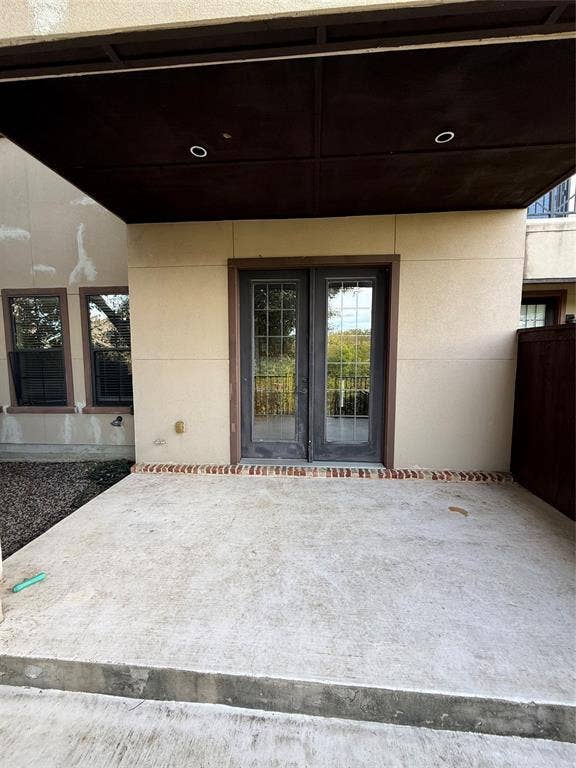 1025 Emerson Park Lane, Irving, TX 75063 Covered concrete patio featuring a brick threshold, dual French doors with multi-pane glass, and recessed ceiling lighting