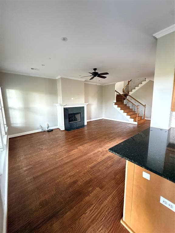 1025 Emerson Park Lane, Irving, TX 75063 Living area featuring wood-finish flooring, a fireplace with a dark stone surround, a central ceiling fan, and a staircase with wood treads and decorative metal balusters