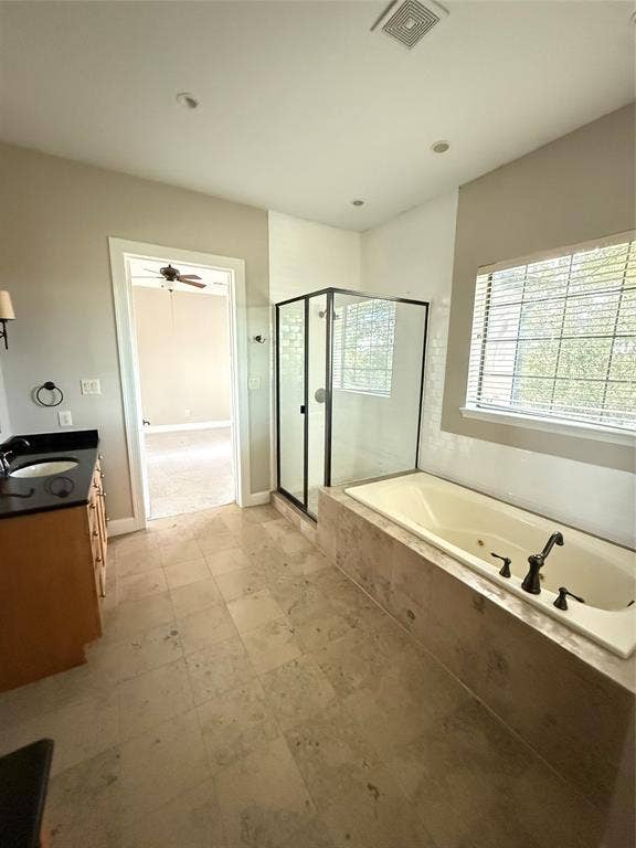 1025 Emerson Park Lane, Irving, TX 75063 Bathroom featuring a soaking tub with tile surround, glass-enclosed shower with matte black frame, dark stone countertop, wood-finish cabinetry, and large-format tile flooring