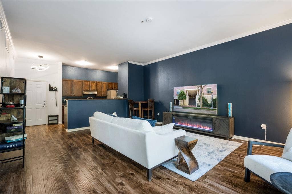 2305 Worthington Street, #103, Dallas, TX 75204 Open-concept interior featuring wood-finish flooring, dark-toned accent wall, crown molding, and recessed lighting