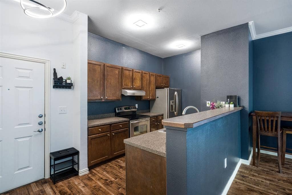 2305 Worthington Street, #103, Dallas, TX 75204 Kitchen featuring wood cabinetry, stone-finish countertops, stainless steel appliances, and wood-finish flooring