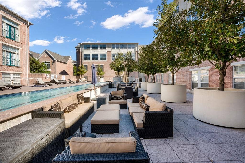 2305 Worthington Street, #103, Dallas, TX 75204 Outdoor pool with tile surround, paved terrace, and oversized cylindrical concrete planters featuring mature trees