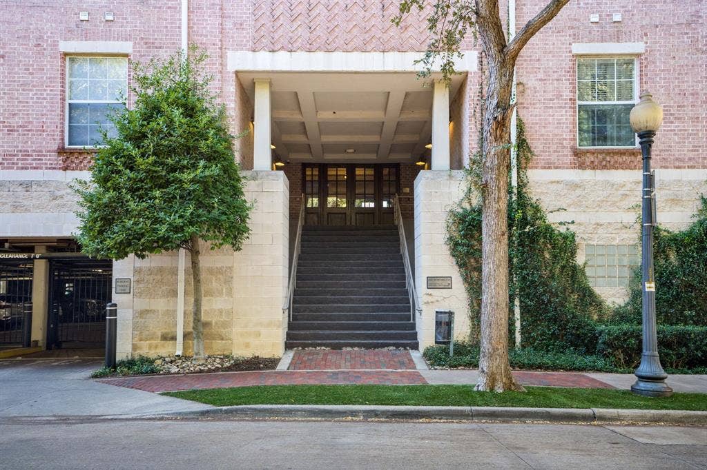 2305 Worthington Street, #103, Dallas, TX 75204 Exterior facade featuring patterned brickwork, stone masonry, a recessed entry with coffered ceilings, multi-pane glass doors, and a grand staircase with metal handrails