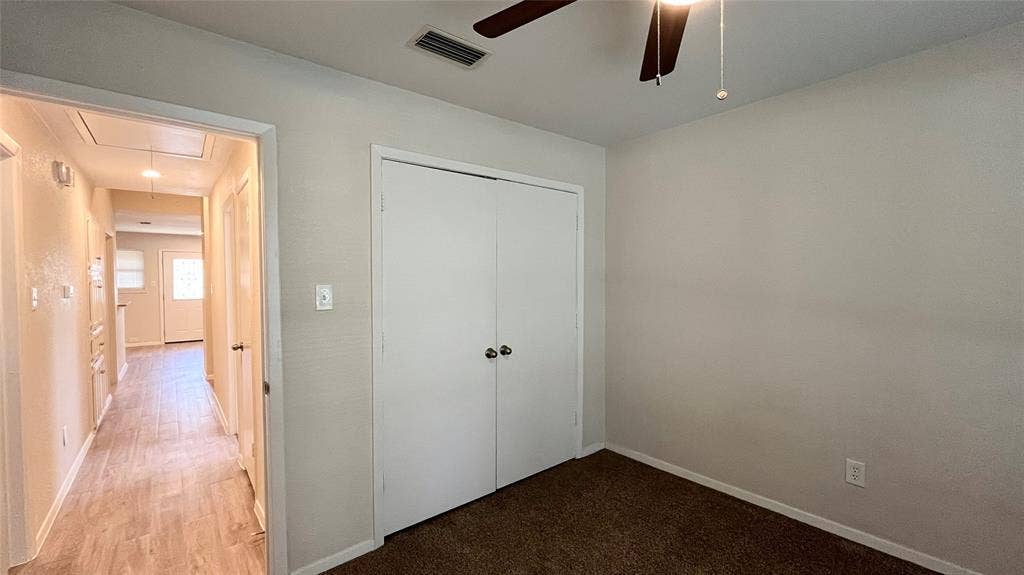 Room featuring brown carpeting, a double-door closet with spherical knobs, and a ceiling fan with integrated lighting