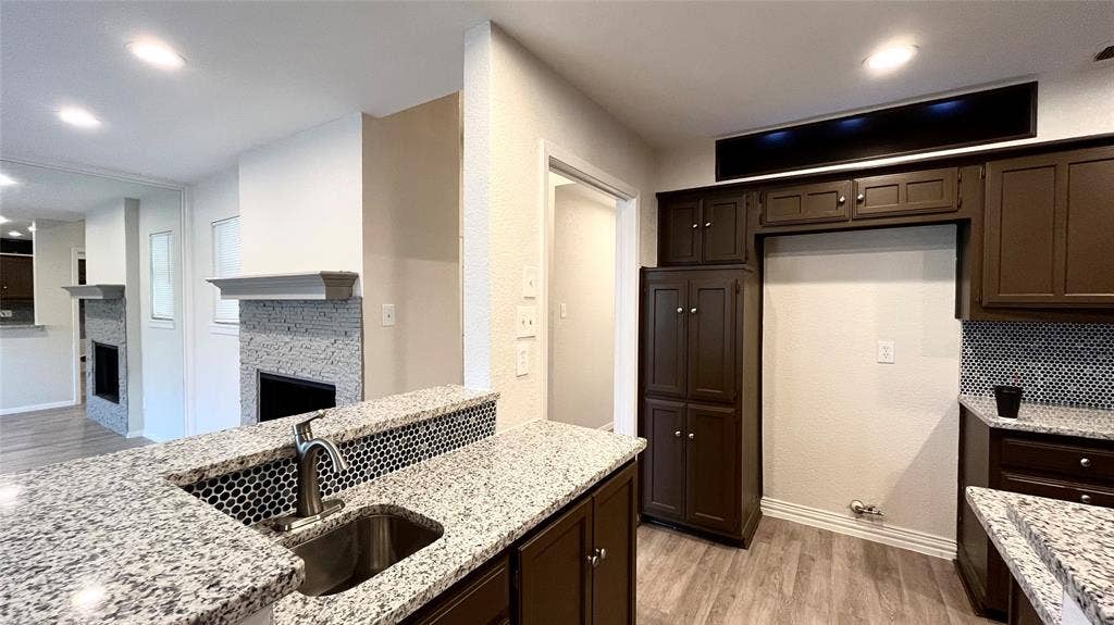 Kitchen featuring dark cabinetry, speckled stone-finish countertops, and an undermount stainless steel sink