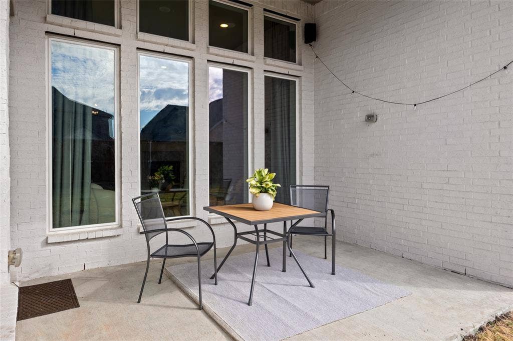 2820 Eccleston Street, Celina, TX 75009 Covered patio featuring white painted brick masonry, concrete flooring, and multiple floor-to-ceiling windows with transoms