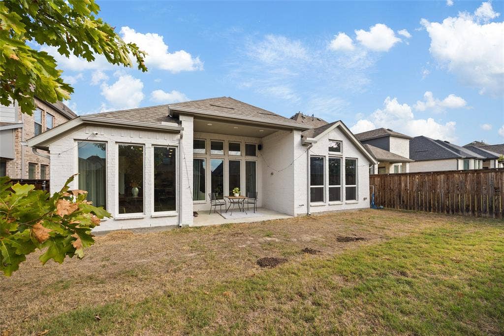 2820 Eccleston Street, Celina, TX 75009 Painted brick exterior featuring a covered patio, expansive windows with grid detailing, and a fenced backyard