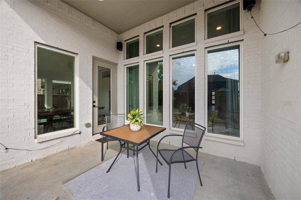 2820 Eccleston Street, Celina, TX 75009 Covered patio featuring a painted brick exterior, concrete flooring, and multiple floor-to-ceiling windows with transoms