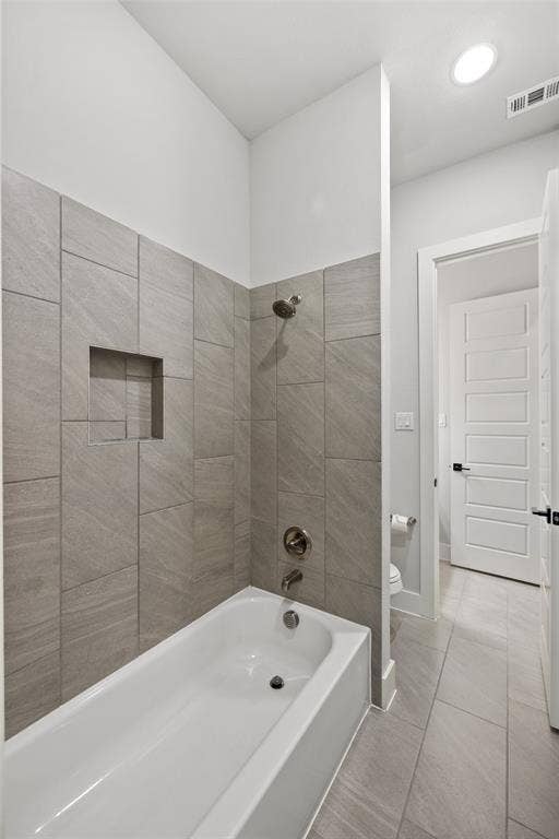 2820 Eccleston Street, Celina, TX 75009 Bathtub with ceramic tile surround, integrated recessed shelving, and metallic shower fixtures, complemented by large-format floor tiling and a five-panel interior door