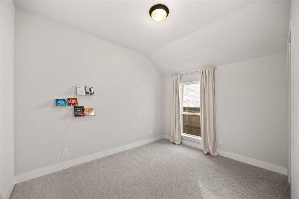 2820 Eccleston Street, Celina, TX 75009 Neutral-toned room featuring vaulted ceilings, neutral carpeting, and a flush-mount ceiling light fixture
