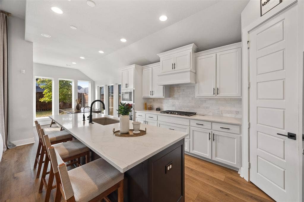 2820 Eccleston Street, Celina, TX 75009 Kitchen featuring white cabinetry, stone countertops, a dark-toned center island, recessed lighting, and wood-finish flooring