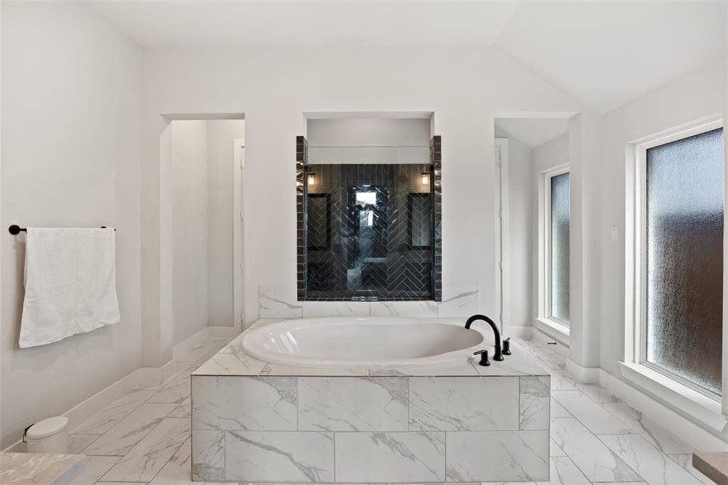 2820 Eccleston Street, Celina, TX 75009 Built-in soaking tub with a tiled surround, herringbone-patterned wall accent, matte black plumbing fixtures, and tile flooring