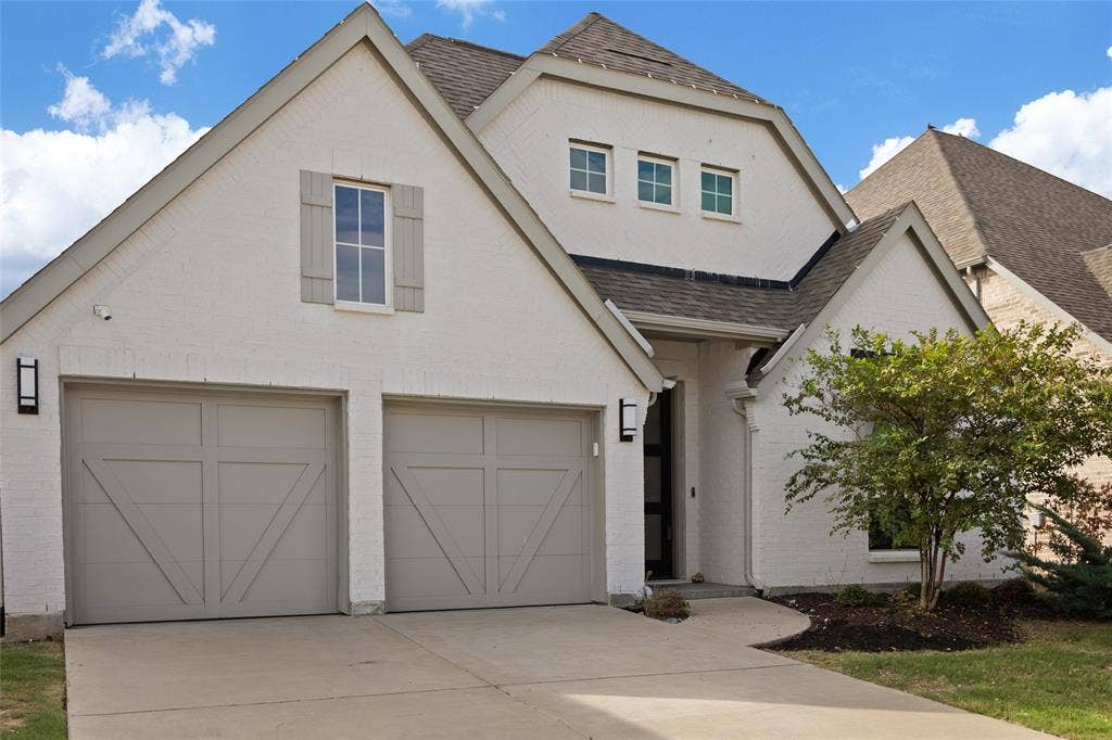 2820 Eccleston Street, Celina, TX 75009 Painted brick exterior with a multi-gabled roofline, two-car garage with carriage-style doors, and decorative exterior shutters