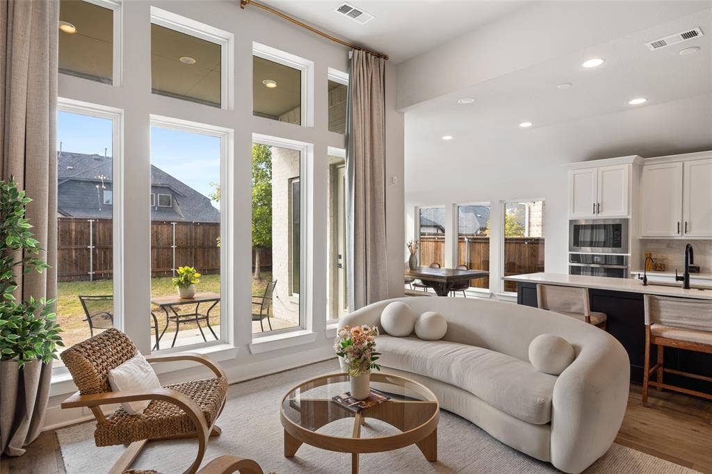 2820 Eccleston Street, Celina, TX 75009 Expansive windows with transom accents, recessed lighting, white cabinetry with contrasting kitchen island, wood-finish flooring, and built-in wall oven and microwave combination