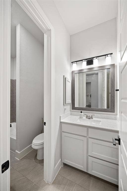 2820 Eccleston Street, Celina, TX 75009 White cabinetry with a solid-surface countertop, rectangular undermount sink, framed mirror, and multi-light vanity fixture, featuring tile flooring