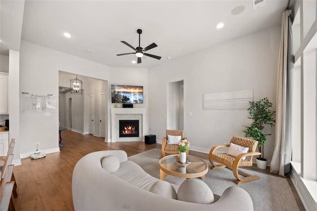 2820 Eccleston Street, Celina, TX 75009 Living area featuring high ceilings, wood-finish flooring, a fireplace with a decorative tile surround, recessed lighting, and a multi-blade ceiling fan