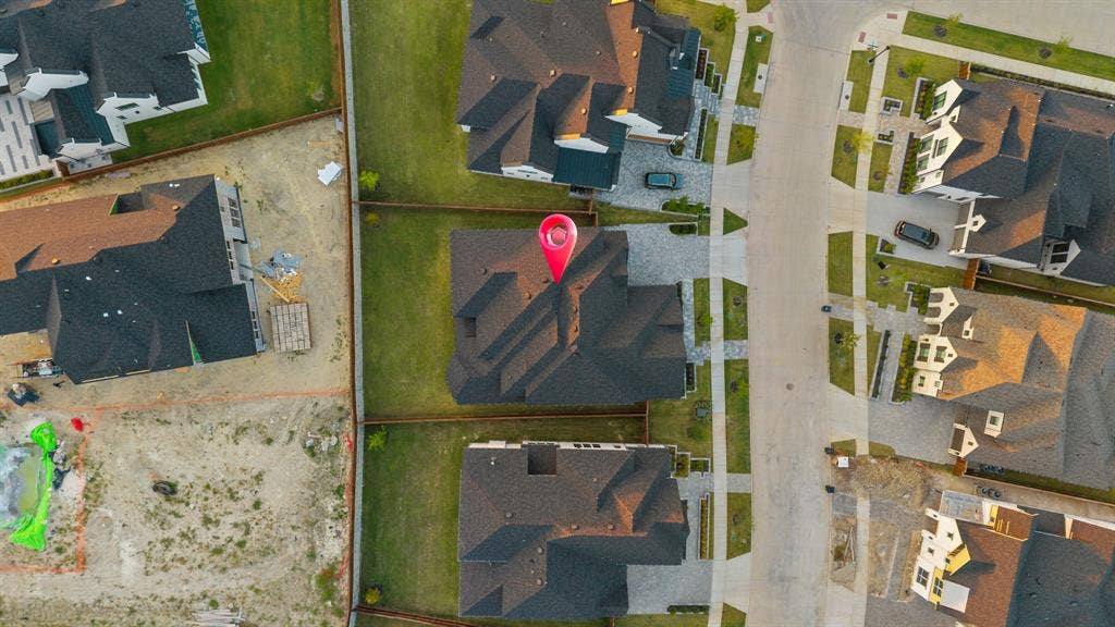 Aerial view of a residential property featuring a multi-gable shingle roof, paved driveway, and established lawn