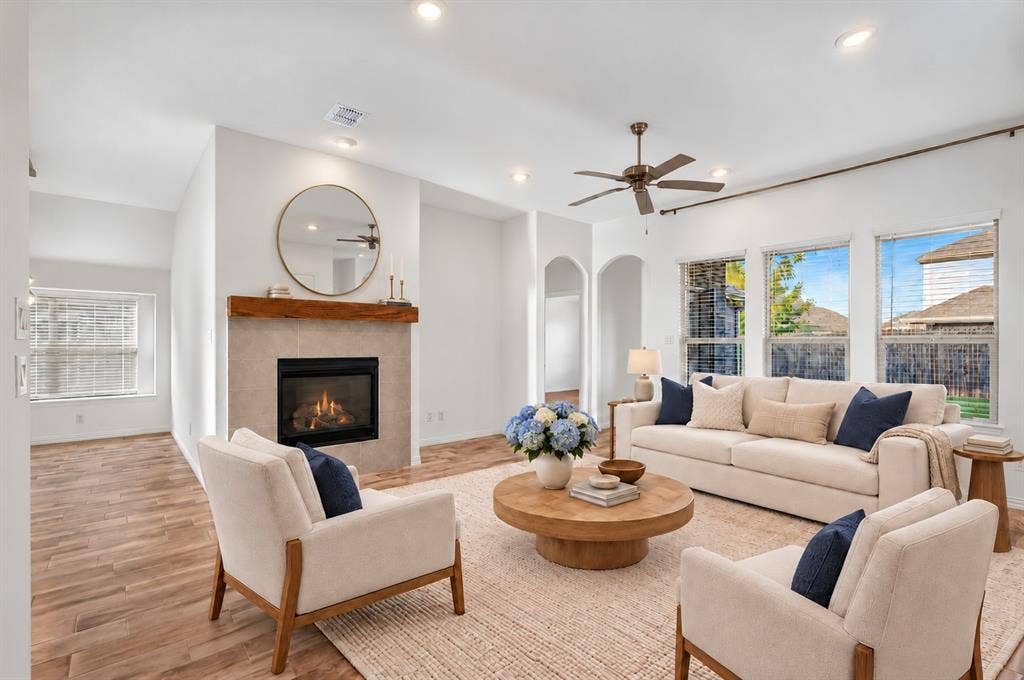 Living area featuring wood-finish flooring, a fireplace with a stone-tile surround and timber mantel, recessed lighting, and a multi-blade ceiling fan